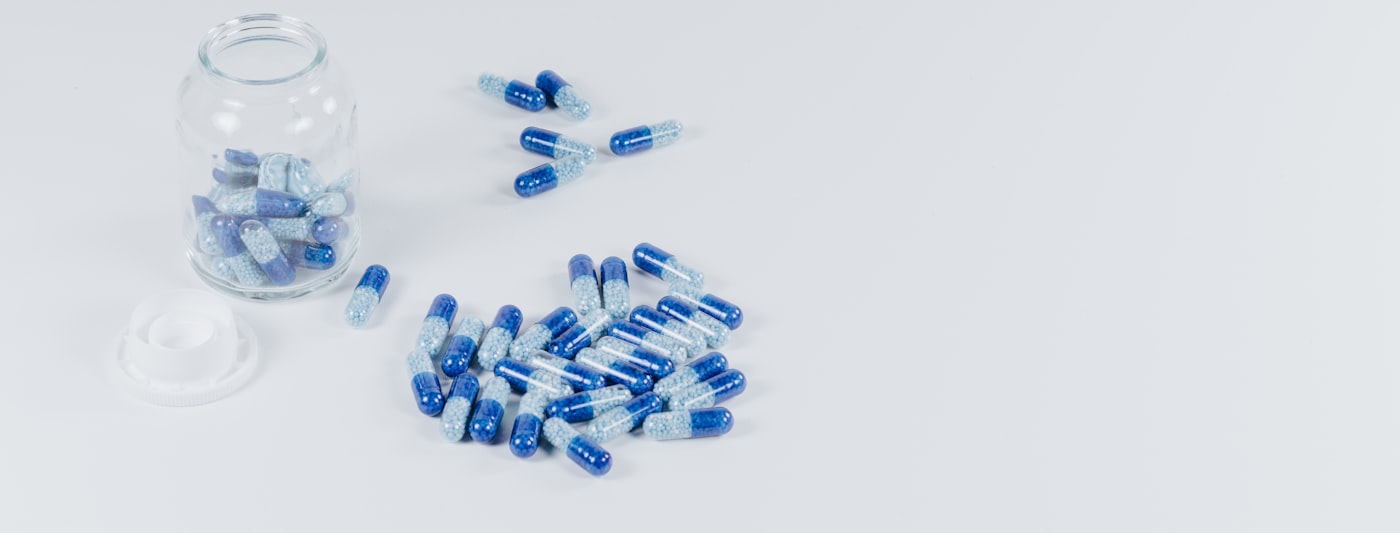 Supplement capsules beside an open jar